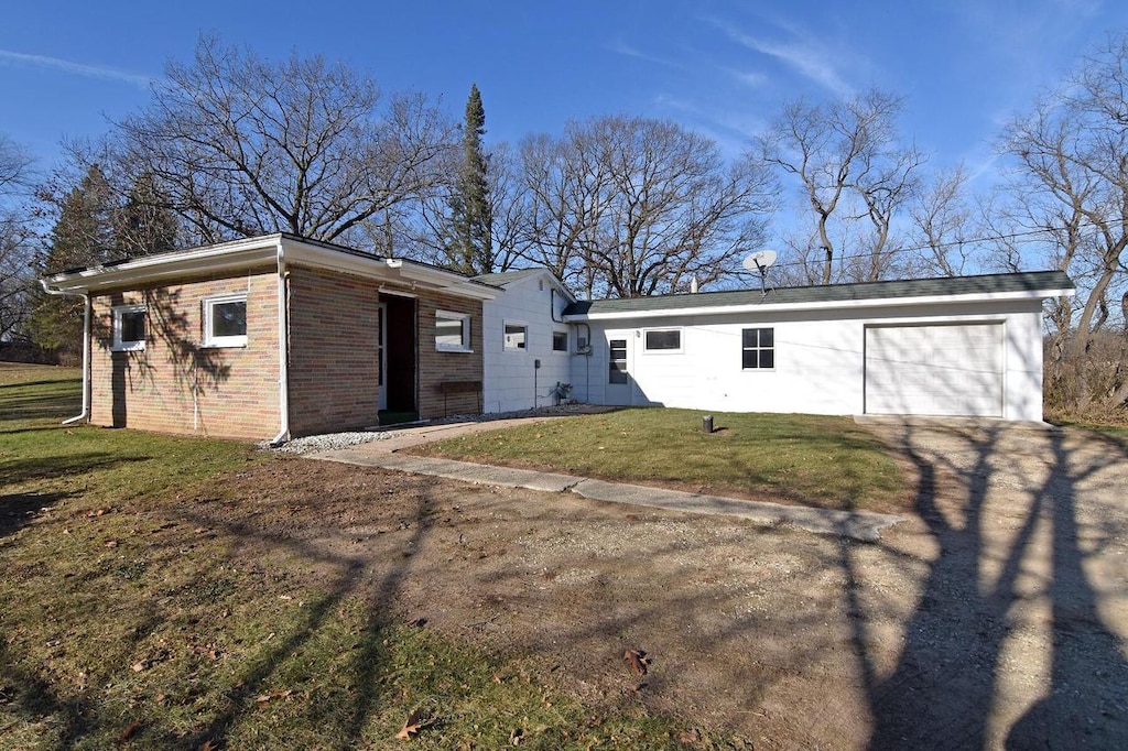 back of property featuring a garage and a lawn