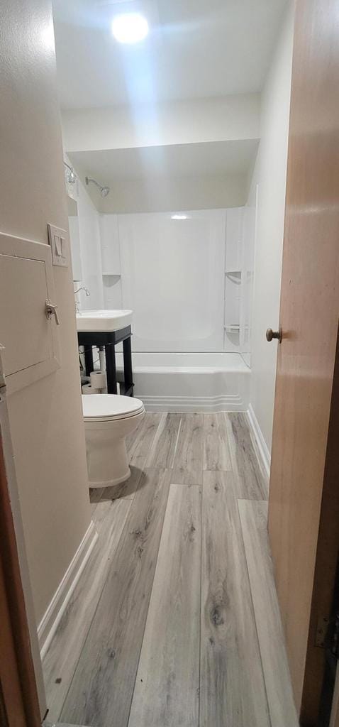 bathroom with hardwood / wood-style floors, toilet, and bathtub / shower combination