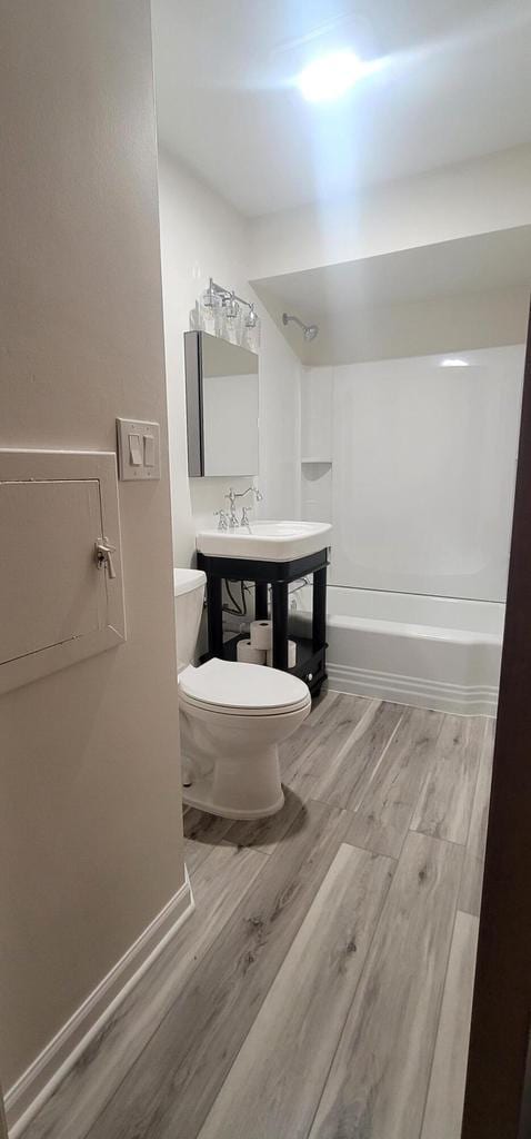 full bathroom with washtub / shower combination, toilet, wood-type flooring, and sink