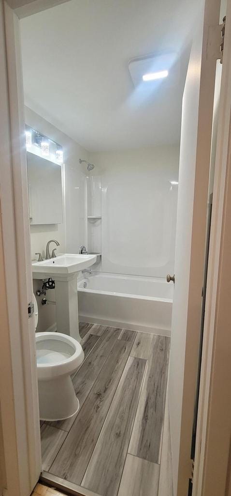 bathroom featuring wood-type flooring, shower / bath combination, and toilet