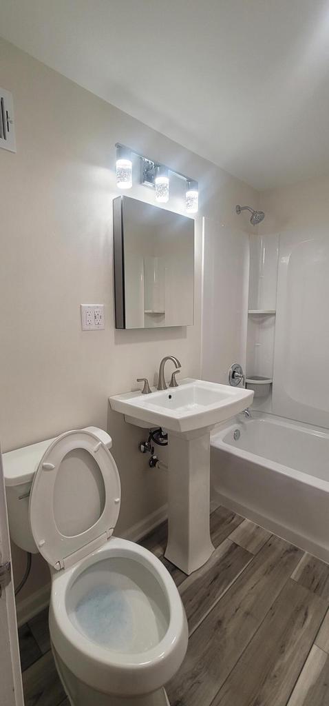 bathroom with bathing tub / shower combination, hardwood / wood-style floors, and toilet