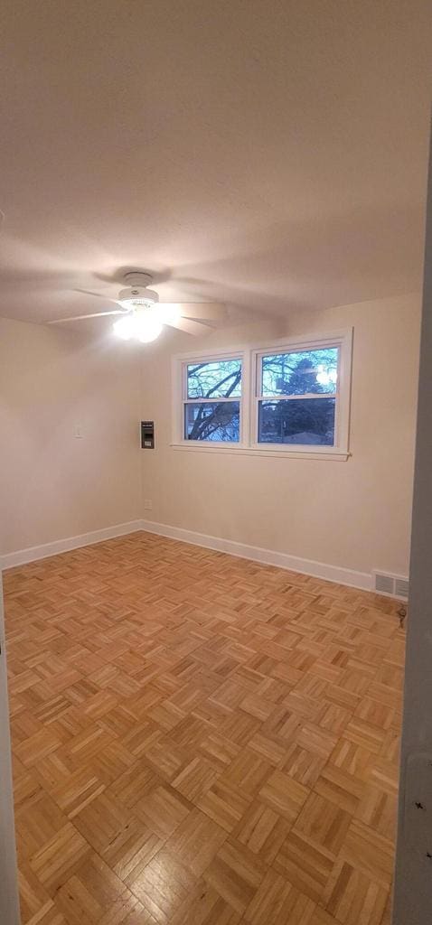 unfurnished room featuring ceiling fan and light parquet flooring