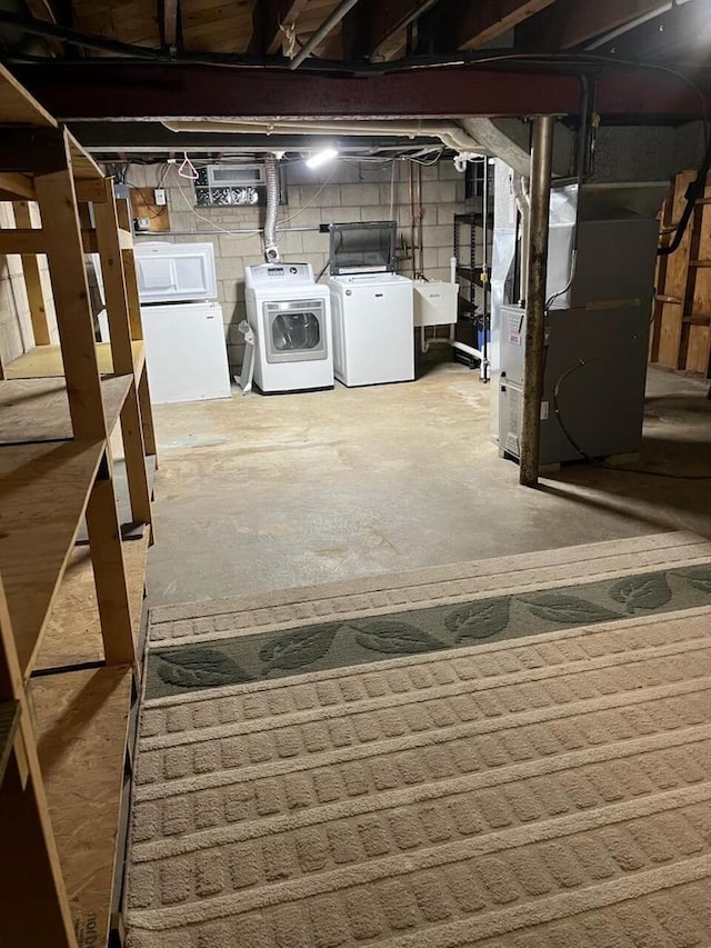 basement with washing machine and dryer, heating unit, and sink