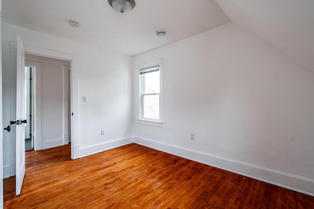 empty room with light hardwood / wood-style floors and vaulted ceiling