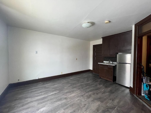 kitchen with stainless steel fridge, dark hardwood / wood-style floors, and dark brown cabinets