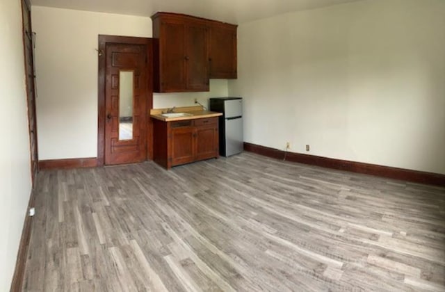 kitchen featuring sink, stainless steel refrigerator, and light hardwood / wood-style flooring