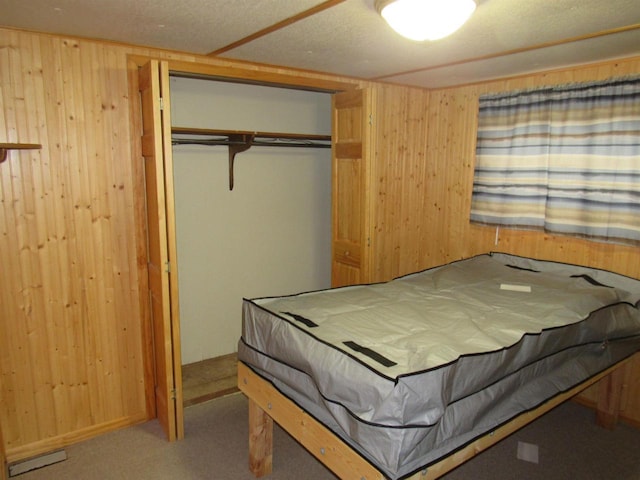 bedroom featuring a textured ceiling, carpet floors, a closet, and wood walls