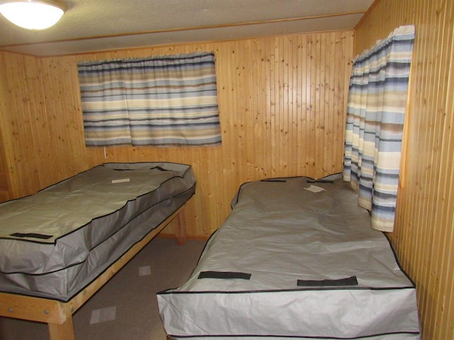 carpeted bedroom featuring wooden walls