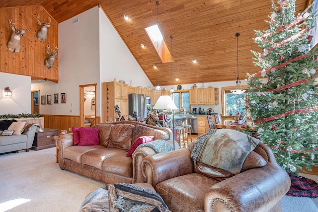 carpeted living room featuring a skylight, high vaulted ceiling, wood ceiling, and wood walls