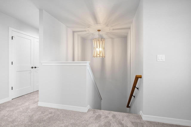 stairway with carpet flooring and a notable chandelier