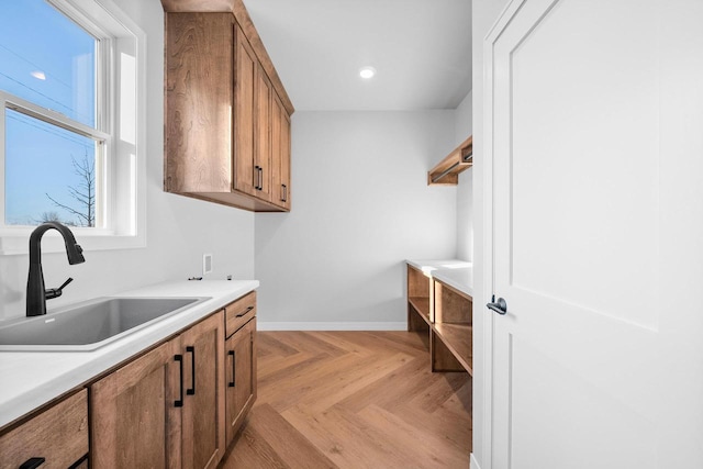 laundry area with hookup for a washing machine, sink, light parquet floors, and cabinets