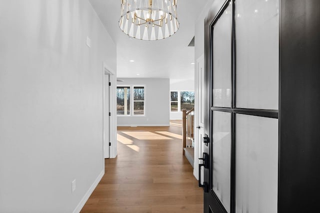 corridor with a chandelier and light wood-type flooring