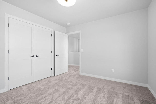 unfurnished bedroom with light colored carpet and a closet