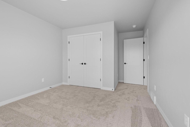 unfurnished bedroom featuring light colored carpet and a closet