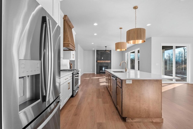 kitchen with white cabinetry, sink, decorative light fixtures, a center island with sink, and appliances with stainless steel finishes