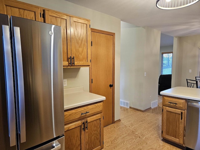 kitchen featuring appliances with stainless steel finishes and light hardwood / wood-style flooring