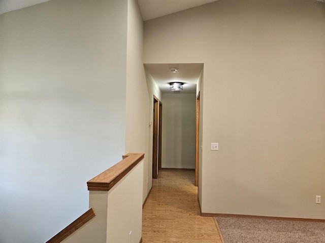 hall with lofted ceiling and light wood-type flooring