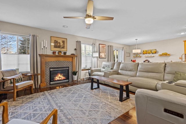 living room with a fireplace, ceiling fan, plenty of natural light, and dark wood-type flooring