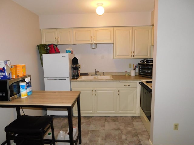 kitchen featuring range, white fridge, and sink