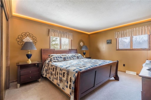 bedroom with a textured ceiling, light colored carpet, and ornamental molding