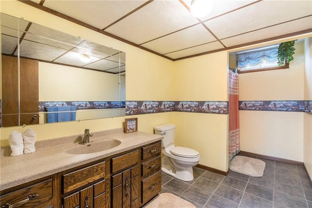 bathroom featuring a drop ceiling, walk in shower, vanity, tile patterned flooring, and toilet