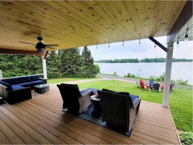 deck featuring a lawn, ceiling fan, a water view, and an outdoor living space