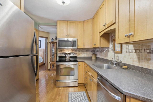 kitchen featuring sink, light wood-type flooring, light brown cabinetry, tasteful backsplash, and stainless steel appliances