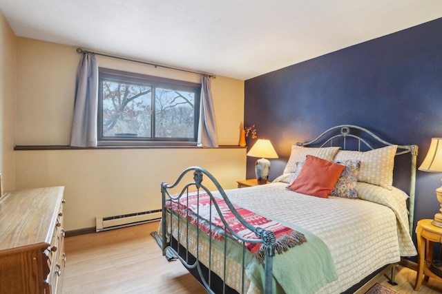 bedroom with light wood-type flooring and a baseboard heating unit