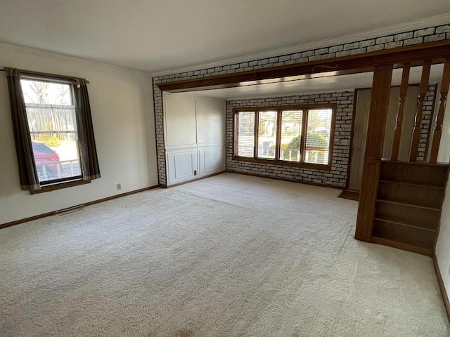 carpeted spare room featuring crown molding and brick wall