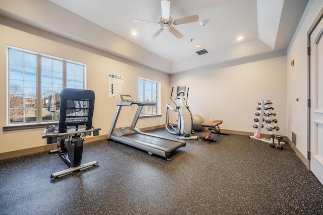 workout room with a raised ceiling and ceiling fan