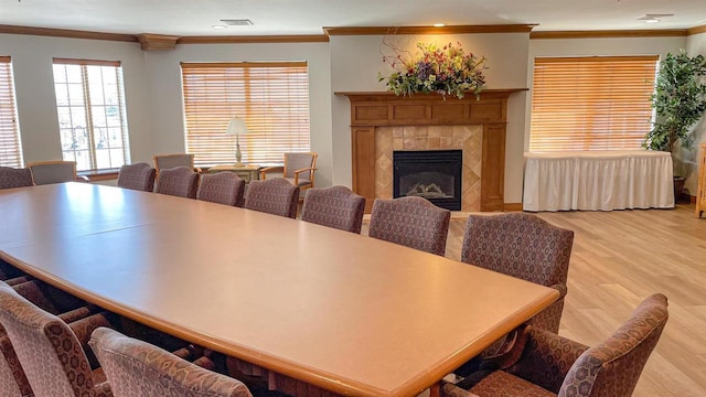 dining area featuring ornamental molding, a tile fireplace, and light hardwood / wood-style flooring