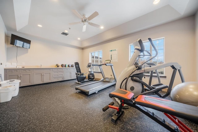 exercise room featuring ceiling fan and a tray ceiling