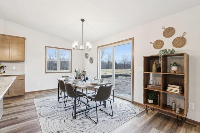 dining room with light wood-type flooring, plenty of natural light, and a notable chandelier