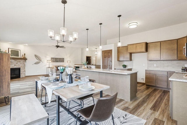 kitchen with dark wood-style floors, decorative light fixtures, a fireplace, tasteful backsplash, and open floor plan