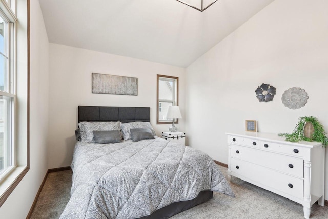 bedroom featuring lofted ceiling, light carpet, and baseboards