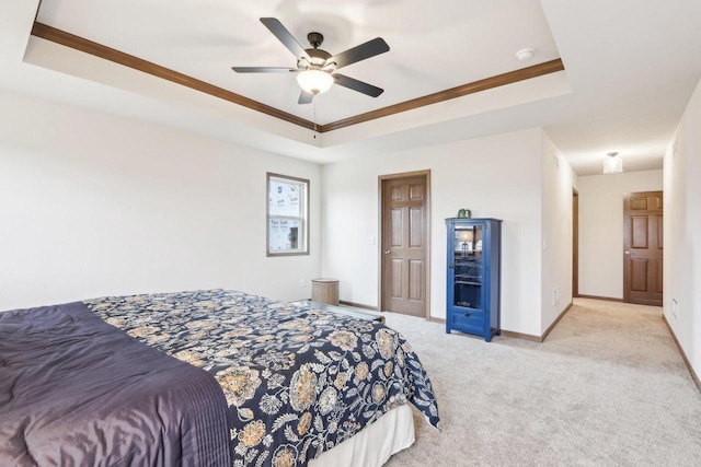 carpeted bedroom featuring baseboards, a raised ceiling, and a ceiling fan