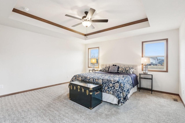 carpeted bedroom with a ceiling fan, a tray ceiling, and baseboards