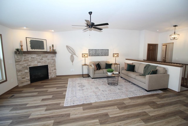 living room with a fireplace, a ceiling fan, vaulted ceiling, wood finished floors, and baseboards