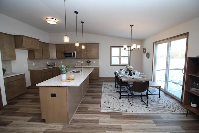 kitchen featuring vaulted ceiling, stainless steel microwave, a sink, and a healthy amount of sunlight