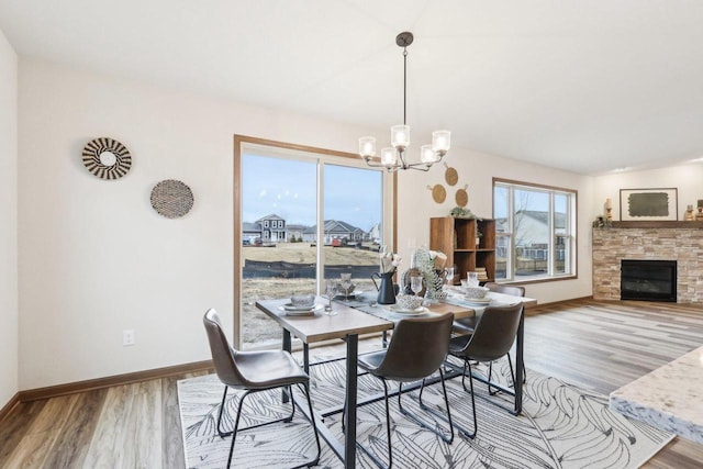 dining area featuring a fireplace, baseboards, a chandelier, and wood finished floors