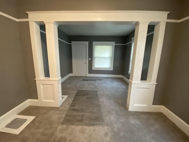 hallway with dark colored carpet and ornate columns