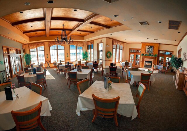 dining area featuring beam ceiling, carpet, a chandelier, and coffered ceiling