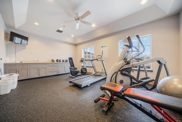 exercise area featuring ceiling fan and a tray ceiling