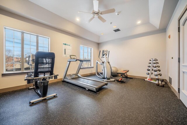 exercise area featuring a raised ceiling and ceiling fan