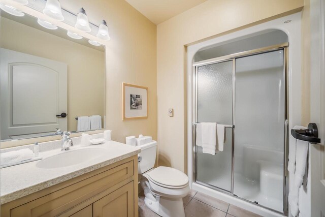 bathroom featuring toilet, vanity, tile patterned floors, and walk in shower