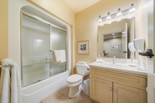 full bathroom featuring tile patterned flooring, vanity, toilet, and combined bath / shower with glass door