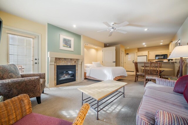 carpeted bedroom featuring ceiling fan, a fireplace, and white fridge