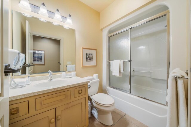 full bathroom featuring tile patterned flooring, vanity, toilet, and bath / shower combo with glass door