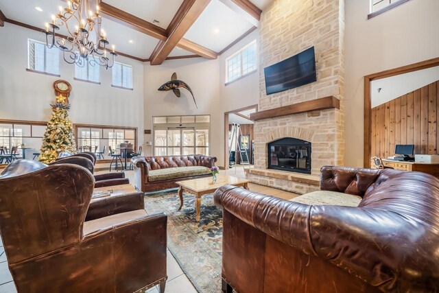 living room with a towering ceiling, a fireplace, light tile patterned floors, and a chandelier