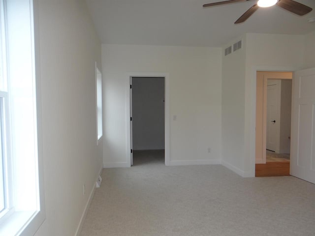 spare room featuring ceiling fan, light colored carpet, and a healthy amount of sunlight